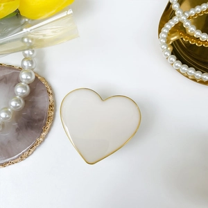 Elegant heart-shaped phone grip with gold frame and white panel on decorative tray