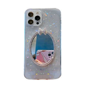 Detail of iPhone case with clear glitter finish, oval makeup mirror and rhinestone bow