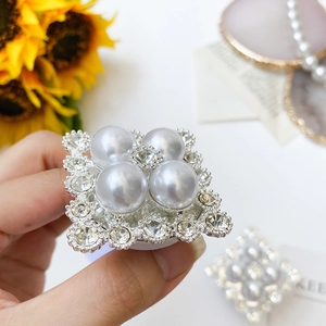 Detail of square phone socket with large white pearls and sparkling rhinestone border