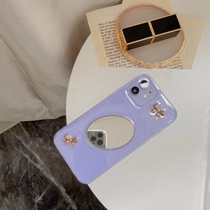 Detail der lila iPhone-Glitzerhülle mit Schminkspiegel und goldenen Schleifen-Dekoren