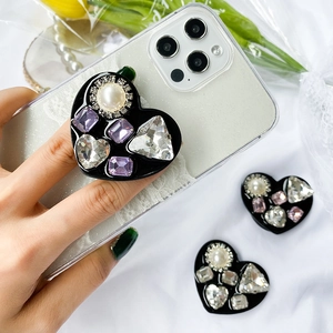 Detailed view of heart-shaped luxury phone grip with inlaid rhinestones and pearls