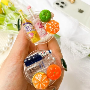 Détail d'un support de téléphone en résine avec bouteilles de bière miniatures et fruits