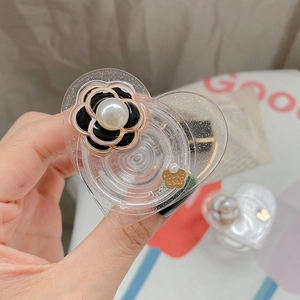 Dettaglio del supporto per telefono a cuore con fiore di camelia, perle e ciondolo a mano