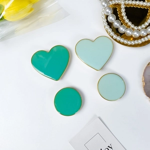 Detail view of heart and round foldaway phone grips with green enamel and gold edges