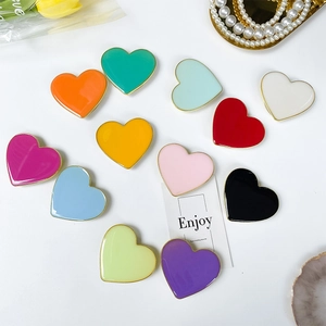 Close-up of 12 colorful heart-shaped foldable phone grips with glossy enamel and metal edges