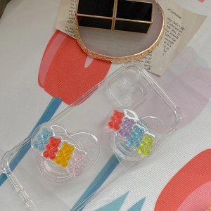 Detail view of heart-shaped phone grips with colorful gummy bears on clear iPhone case