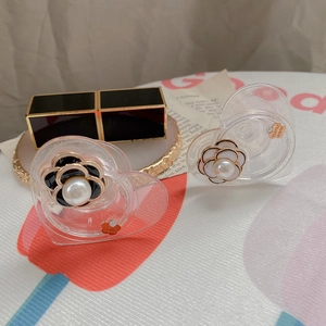 Dettaglio clip a forma di cuore con fiore di camelia, perle e targhetta in metallo fatta a mano