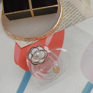 Dettaglio del supporto per telefono a camelia con perla e base a cuore con glitter
