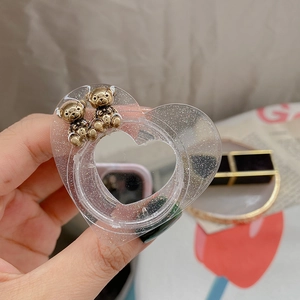 Detail of heart-shaped glitter phone stand with two golden bear charms on acrylic