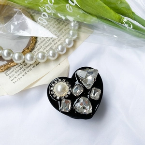 Close-up of luxury heart phone grip with crystals and pearls on elegant white fabric