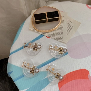 Detail of heart-shaped phone grip with gold rabbit and bear charms on vintage background
