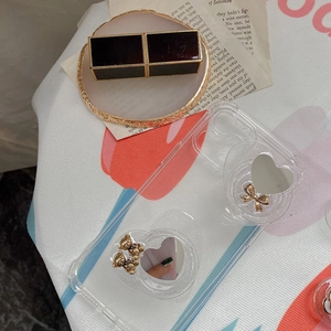 Macro detail of transparent glitter phone case with heart mirrors and gold bear charms