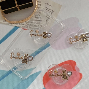 Detail of luxury heart-shaped phone grip with vintage bear, rabbit, and pearl accents