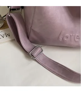 Detail of purple tote bag showing litchi grain leather texture and love embossed logo