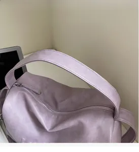 Detail of purple leather tote bag showing handle stitching and smooth metal zipper