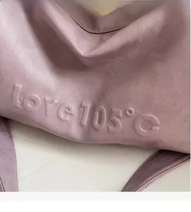 Close-up of purple faux leather tote bag featuring 3D embossed love 105 degree lettering