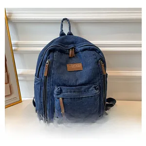 Detail view of washed denim backpack with brown leather zipper pulls and logo patch