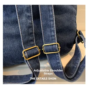 Detail view of denim backpack showing adjustable shoulder straps and brass buckles