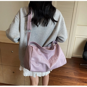 Detail showing lavender faux leather tote with 3D embossed text and wide shoulder strap