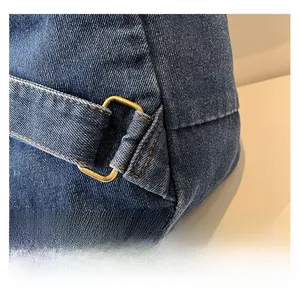 Detailed macro view of dark blue denim fabric with orange stitching and brass buckle