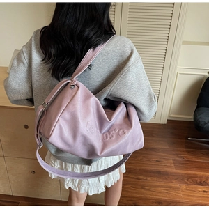 Detail of lavender PU leather tote bag with embossed letters worn by model in a room