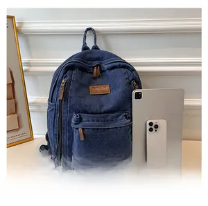Deep blue denim backpack detail with brown leather pulls next to iPad for size comparison