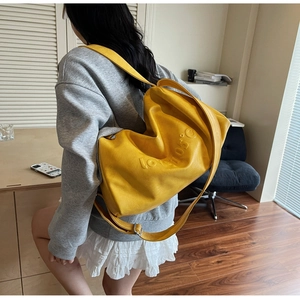Macro detail of yellow crossbody tote bag featuring 3D embossed lettering and leather texture