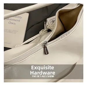 Detail of white leather tote bag featuring a premium metal zipper and smooth inner lining