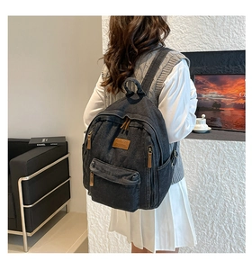Close-up of black washed canvas backpack with leather zip pulls and vintage textures