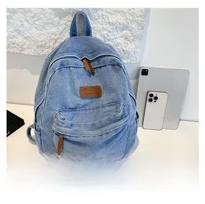 Size comparison of blue denim backpack showing leather logo and large front pocket