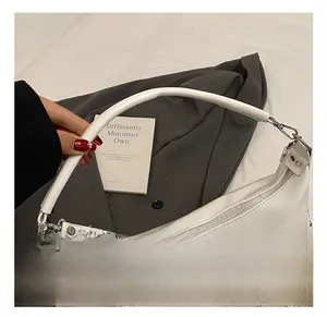 Detail of off-white leather tote bag showing slim handle and front zipper pocket detail