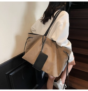Vista laterale di una grande borsa tote in tela kaki con manici in pelle nera e mini custodia