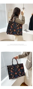 Detailed view of floral embroidery on a vintage canvas tote bag with metal charm