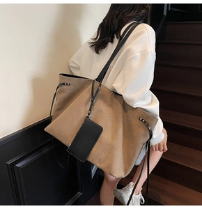Dettaglio borsa tote in tela marrone con manici in pelle nera e porta carte appeso laterale