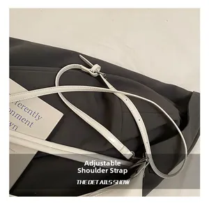 Close-up of adjustable leather shoulder strap with silver metal buckle on a white tote bag