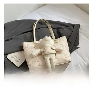 Dettaglio della borsa tote crema con stampa orsetto e ciondolo in peluche con manici