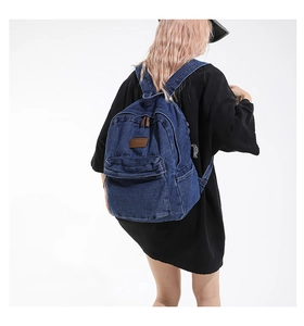 Detail view of vintage denim backpack with brown leather patch and wash texture