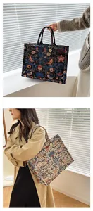 Close-up of floral and bird embroidery on canvas tote bag with metal charm detail