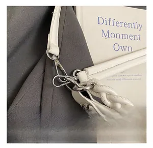 Detail of silver metal hook and woven handle on a white leather commuter tote bag