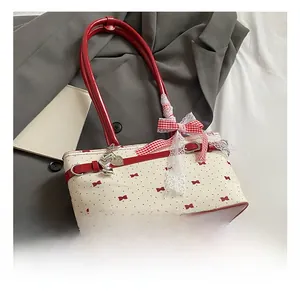 Détail du sac blanc avec nœuds rouges, dentelle et pendentif cœur en métal