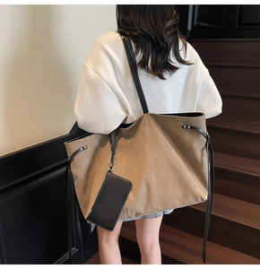 Dettaglio di una grande borsa tote in tela kaki con sottili manici neri e astuccio