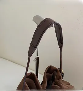 Detail of wide leather shoulder strap and soft suede texture on brown tote bag