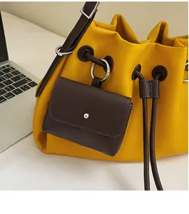 Detail of yellow drawstring bucket bag with a dark brown detachable mini flap pocket