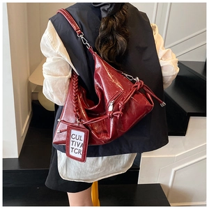 Detail of burgundy glossy patent leather tote with woven handle and silver hardware