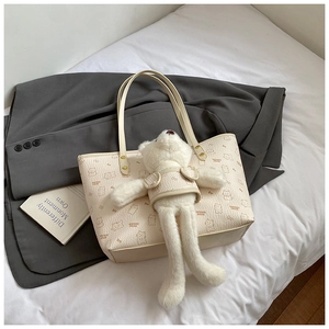 Detail of cream leather tote bag with bear pattern and matching plush bear charm