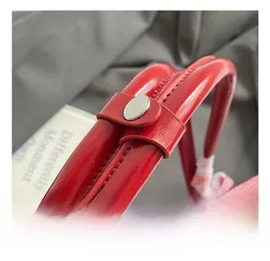 Détail du sac à main en cuir verni rouge brillant avec surpiqûres et bouton argenté
