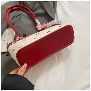 Détail du sac oreiller à nœud rose avec poignée rouge et dentelle à carreaux