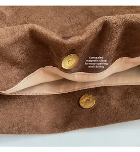 Detail view of the hidden magnetic clasp on a brown suede tote bag with fabric lining