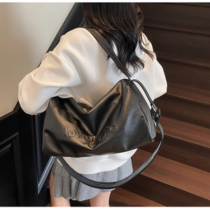 Detail of black leather tote bag with embossed love 105°C lettering on textured surface