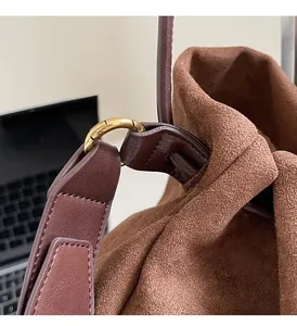 Detail of brown suede tote bag with reinforced leather strap and golden hardware